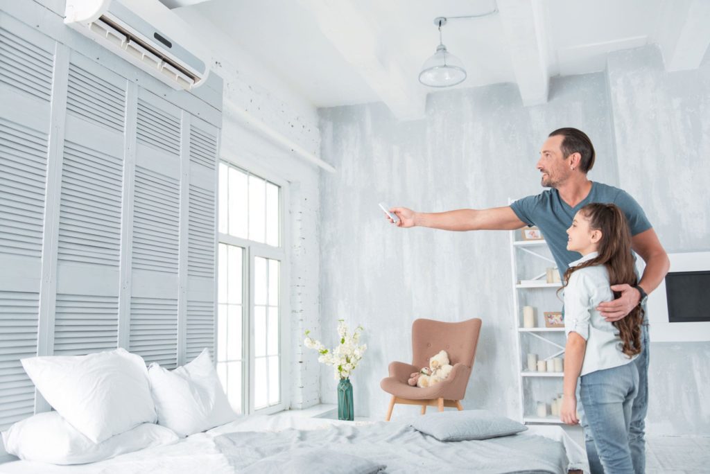 Man with girl uses remote control for ductless ac