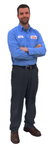 A man in a blue work shirt and dark pants stands with his arms crossed, wearing brown shoes and a name tag—ready to assist and always earning positive service reviews.
