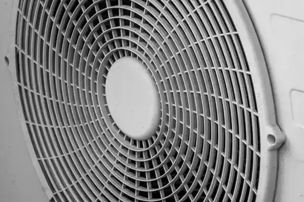 Close-up view of a round, metal fan grill with concentric circular patterns and a central solid hub, typically found on heat pump repair units in White Plains, NY.