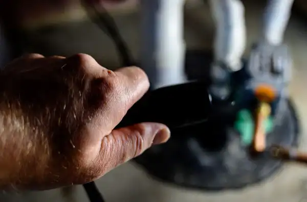 A close-up of a person's hand holding a remote control in White Plains, NY, with blurred objects in the background—perfect for relaxing after a long day of sump pump installation.