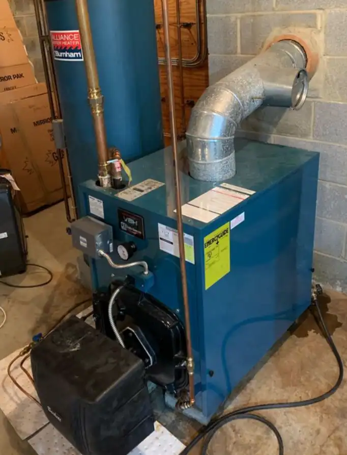 A blue boiler unit with attached pipes and ductwork is situated in a basement with a concrete floor and cinder block walls.